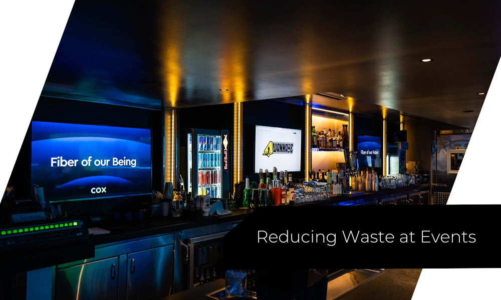 Bar area at a corporate event with blue neon lighting and multiple screens, including a banner about reducing waste.